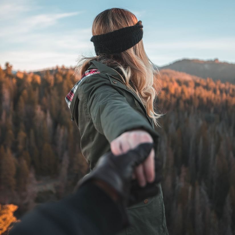 POV of a man holding his partner's hand against a pine backdrop