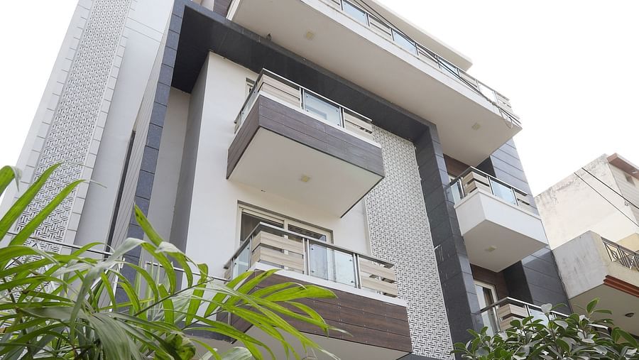 An exterior shot of a contemporary building with angular design and greenery visible in the foreground - Asian Suites Cyber Park, Gurgaon