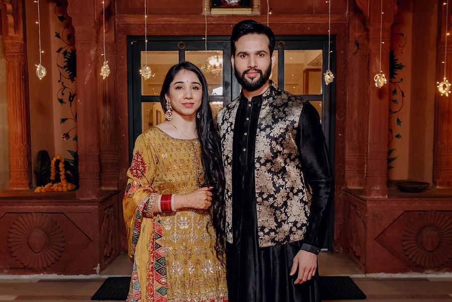 A couple stands together, dressed in traditional attire with soft lighting in the background- Umaid Palace - Best Luxury Heritage Resort Near Jaipur