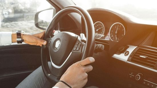 a close up image of the hands of a driver on a steering wheel
