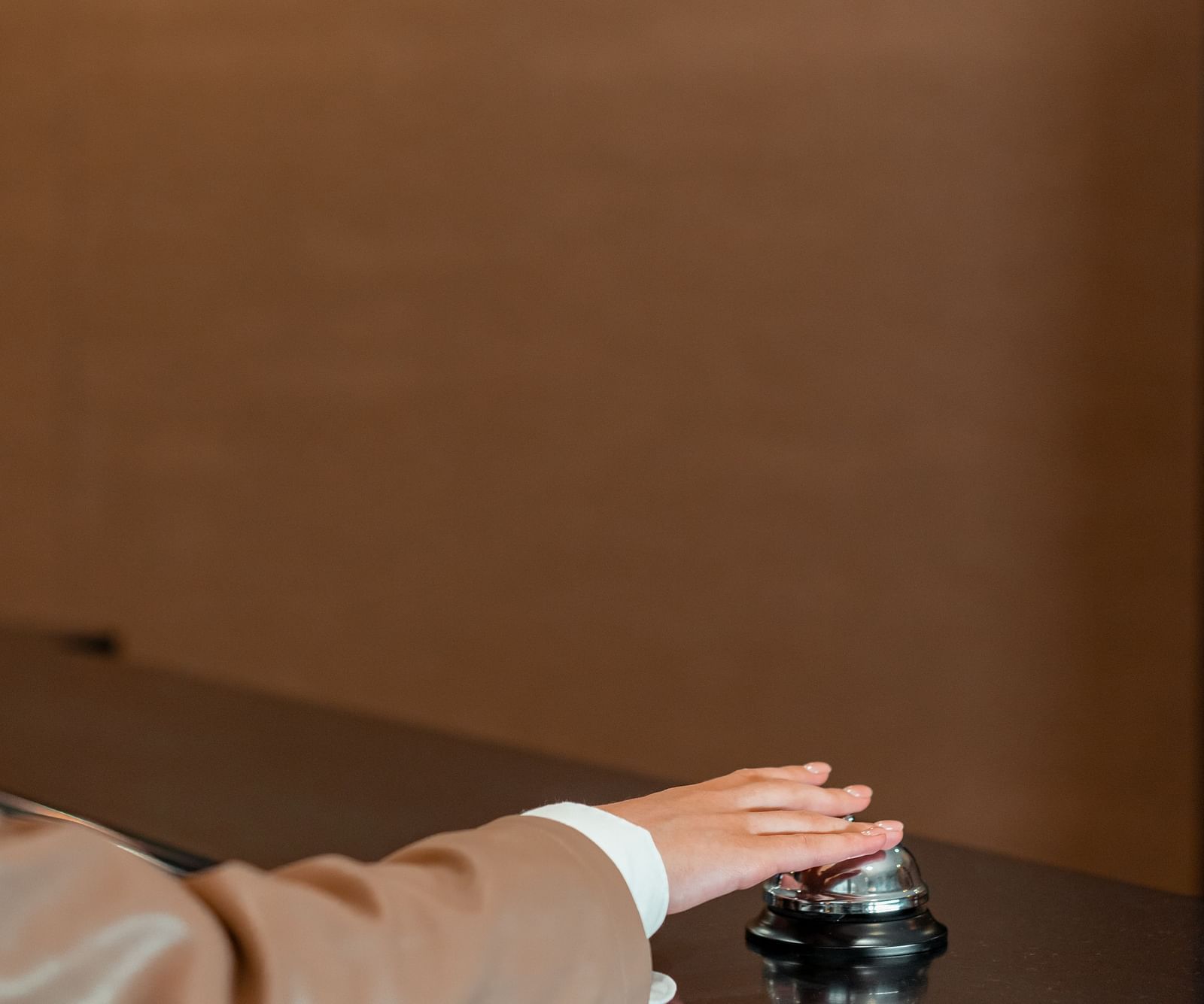 A person hitting a call bell at a hotel reception