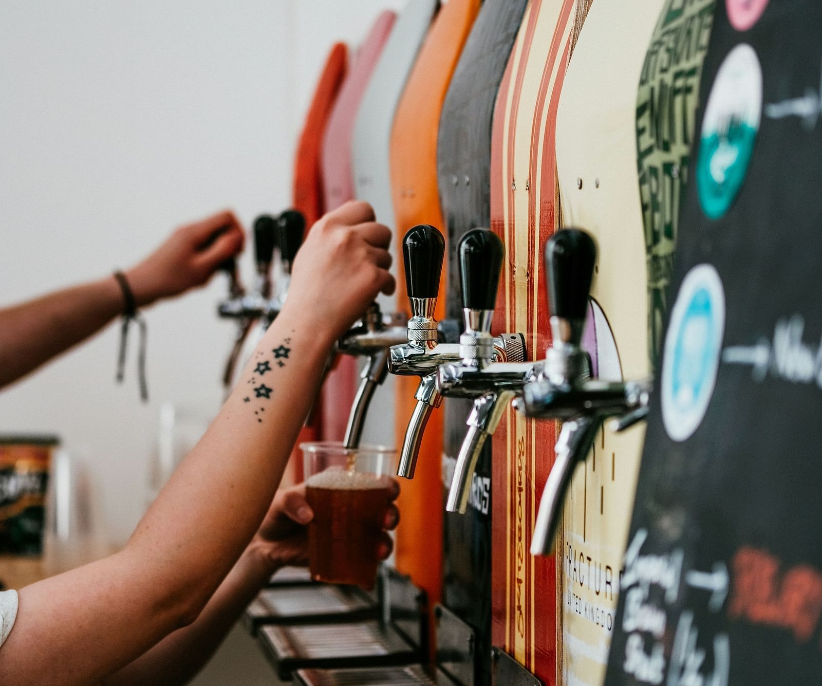 A person pouring beer into a glass from the many taps in view