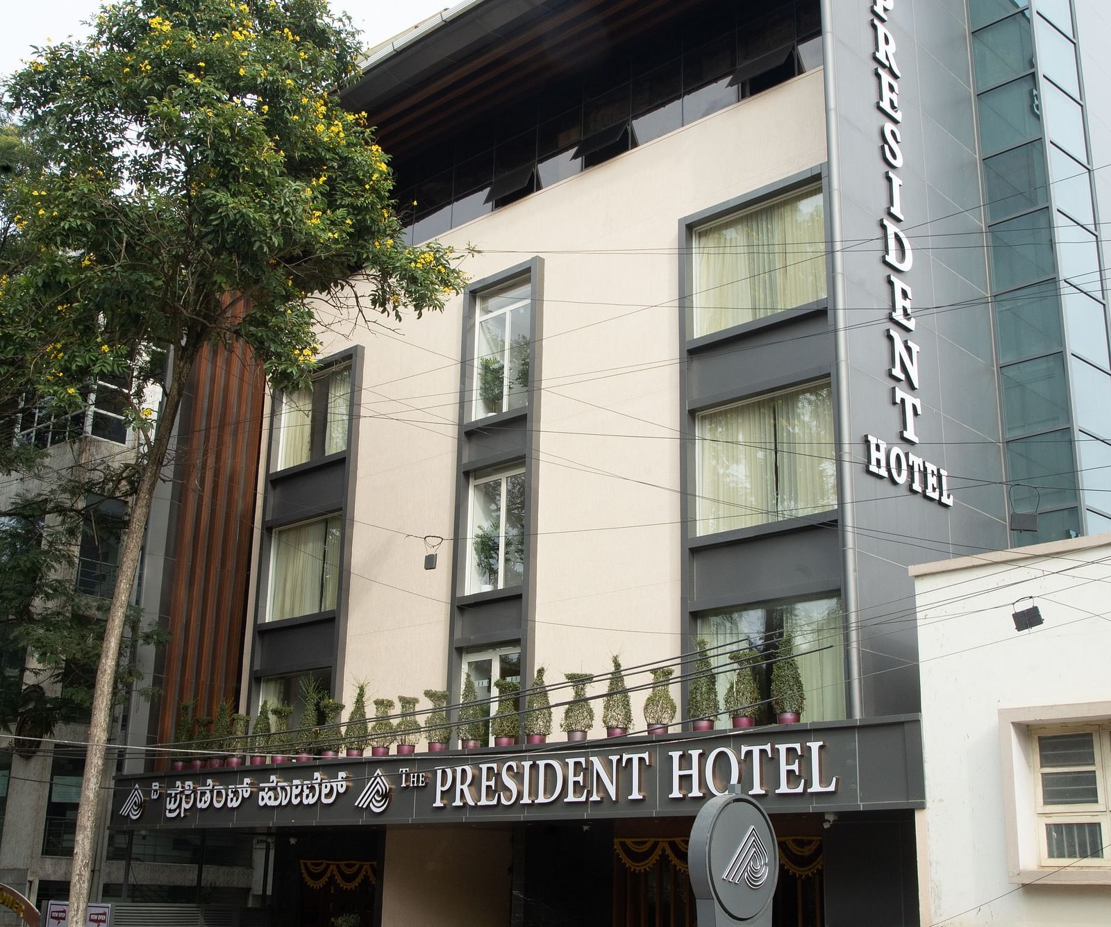 An image of frontal view of a hotel's exterior showcasing its architecture and entrance - The President Hotel, Kumara Park, Bangalore