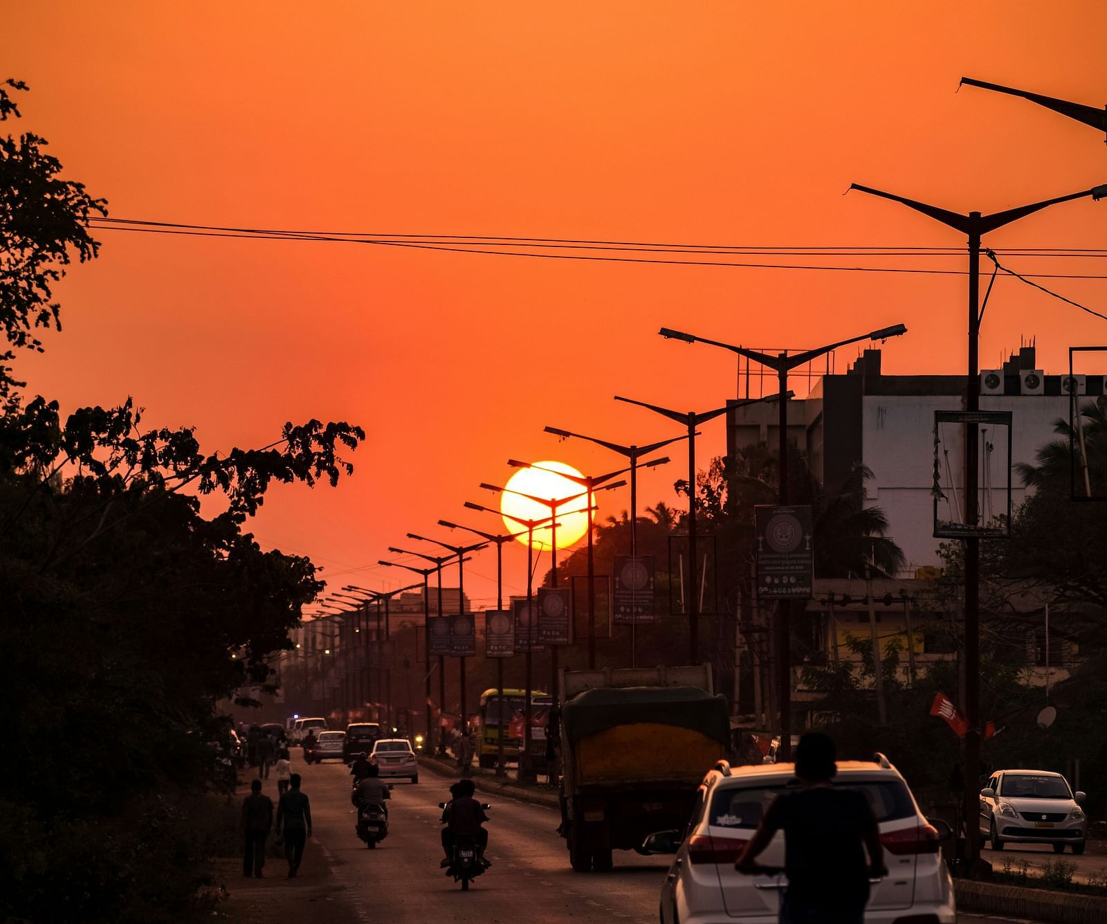 An image of vehicles travelling on a road with the sun setting in the background