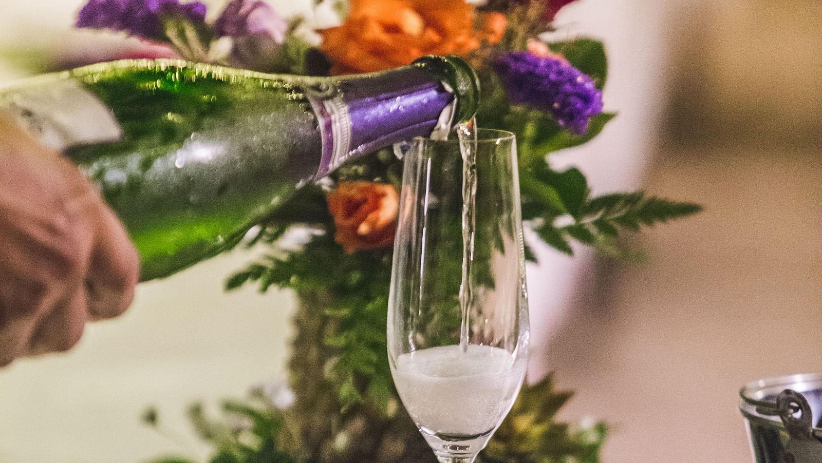 A person pouring sparkling wine in a glass, floral decorations nearby - Maikhao Dream Villa Resort & Spa, Phuket 