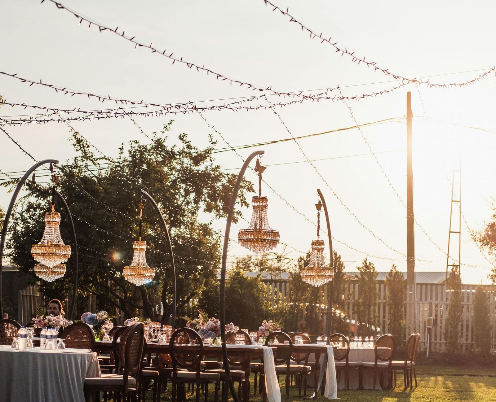 A beautiful lush green lawn area on a bright evening with decorative strings hanging from the tall poles.