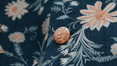 Close-up of embroidered floral fabric with decorative buttons.