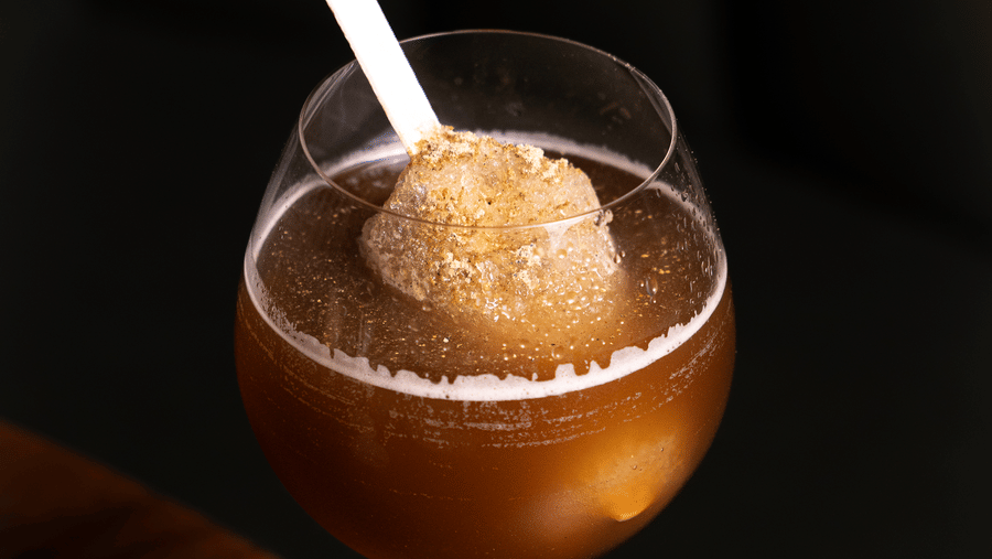 A chilled cocktail served in a wine glass with a white straw, offering a refreshing and elegant touch at Papaya Tree Hotels.