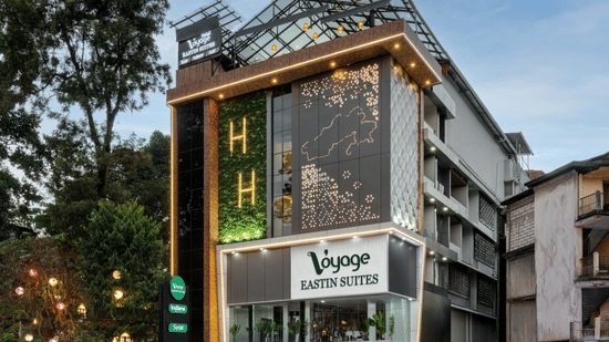 The exterior of a multi-storey hotel building with large windows and an entrance on the ground floor, surrounded by trees and greenery | Voyage Eastin Suites