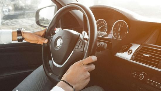 a close up image of the hands of a driver on a steering wheel