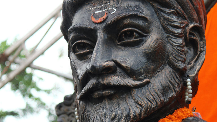 A close up of the statue of Shivaji Maharaj with a garland - History Shivaji Maharaj Marathi.