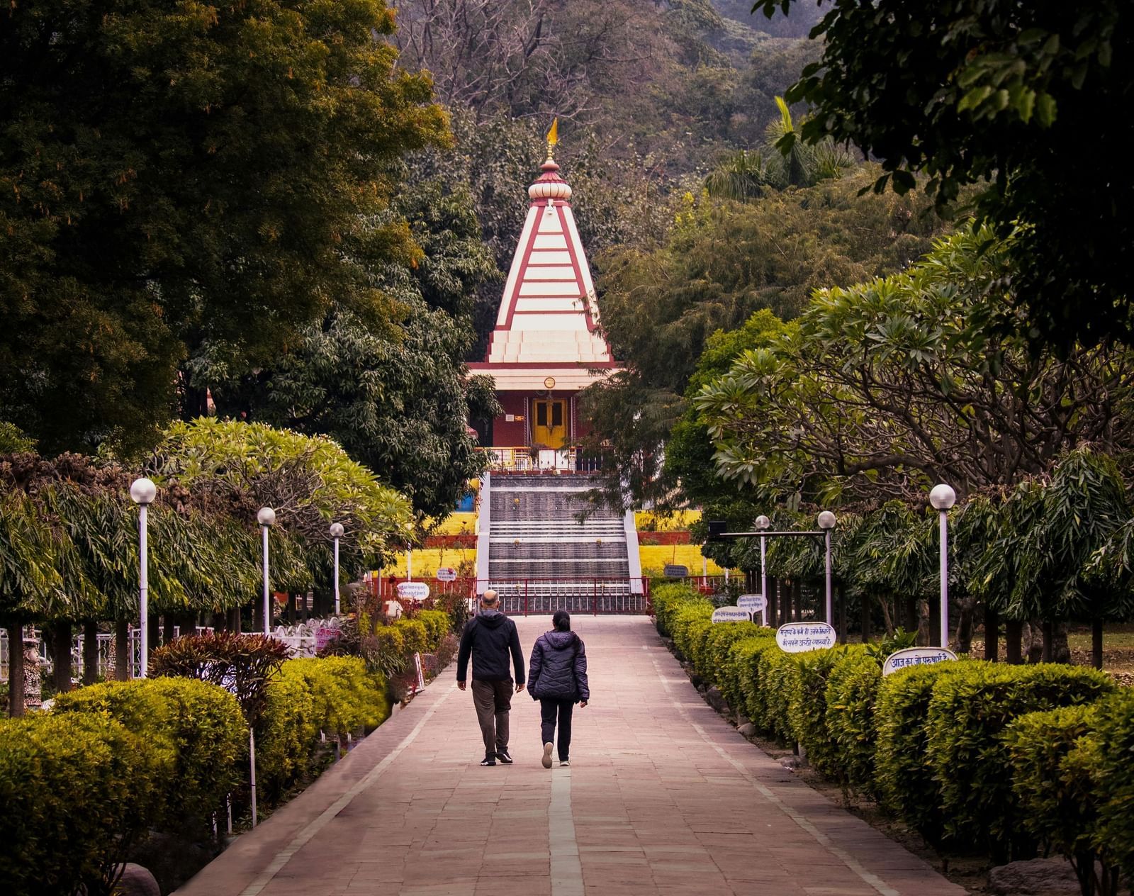 A building surrounded by a long path, with lush gardens on both sides.