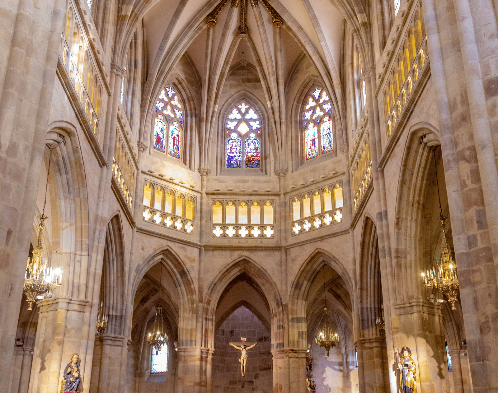 A grand Gothic-style cathedral with soaring vaulted ceilings and colourful stained-glass windows.