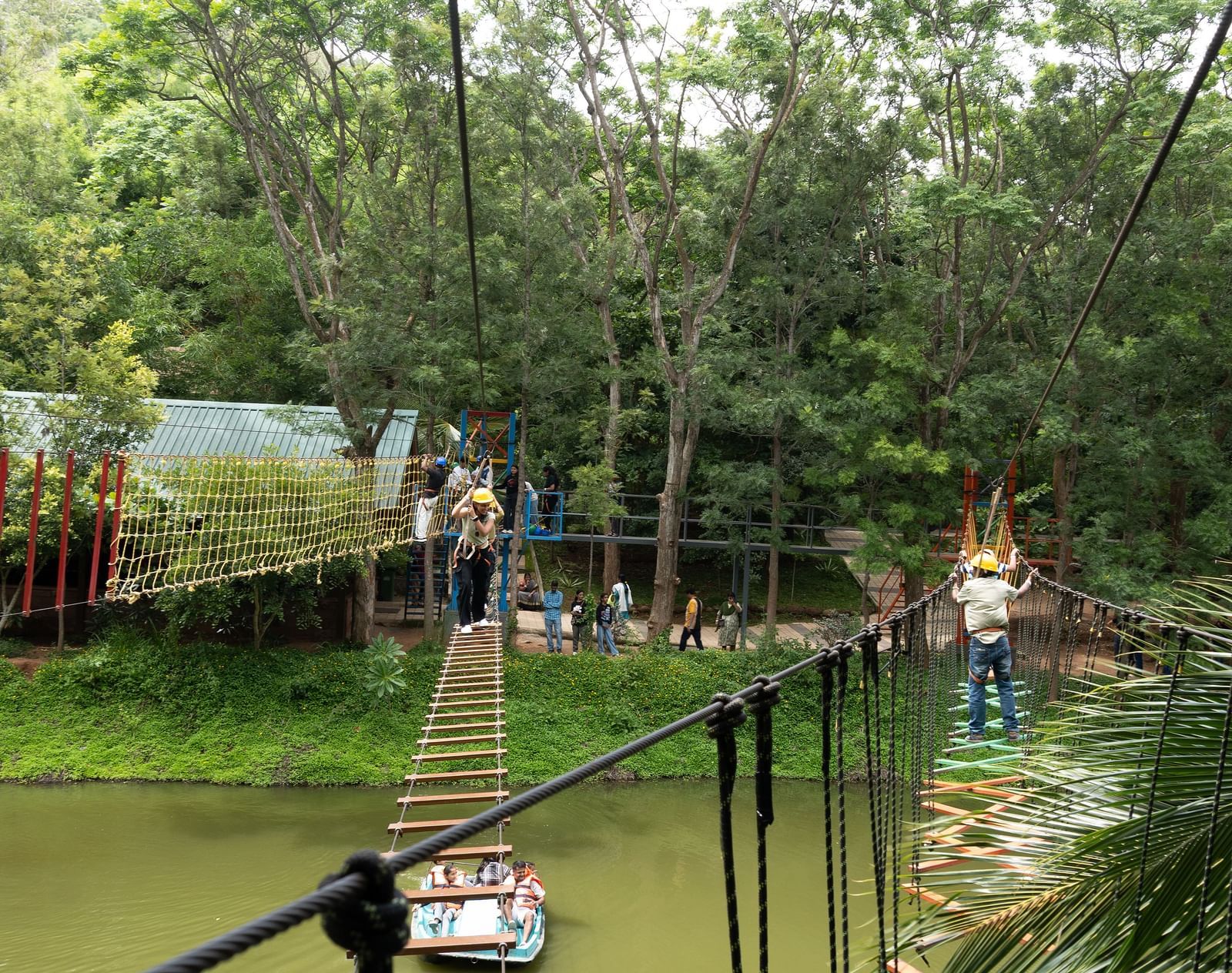An outdoor adventure course features a ladder bridge and other obstacles over a grassy area | RD's Nature Retreat, Bangalore