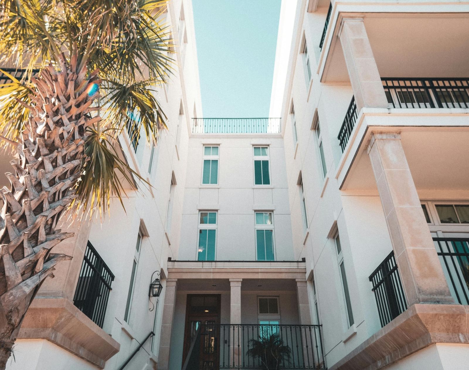 A low-angle shot of a white building with arched doorways under a bright blue sky.