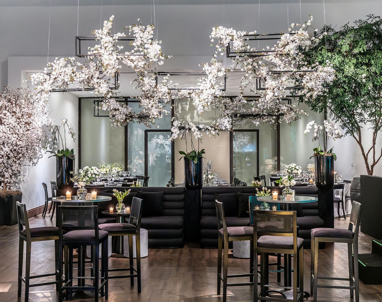 Elegant dining area with dark furniture, decorative white branches, and a glossy wooden floor.