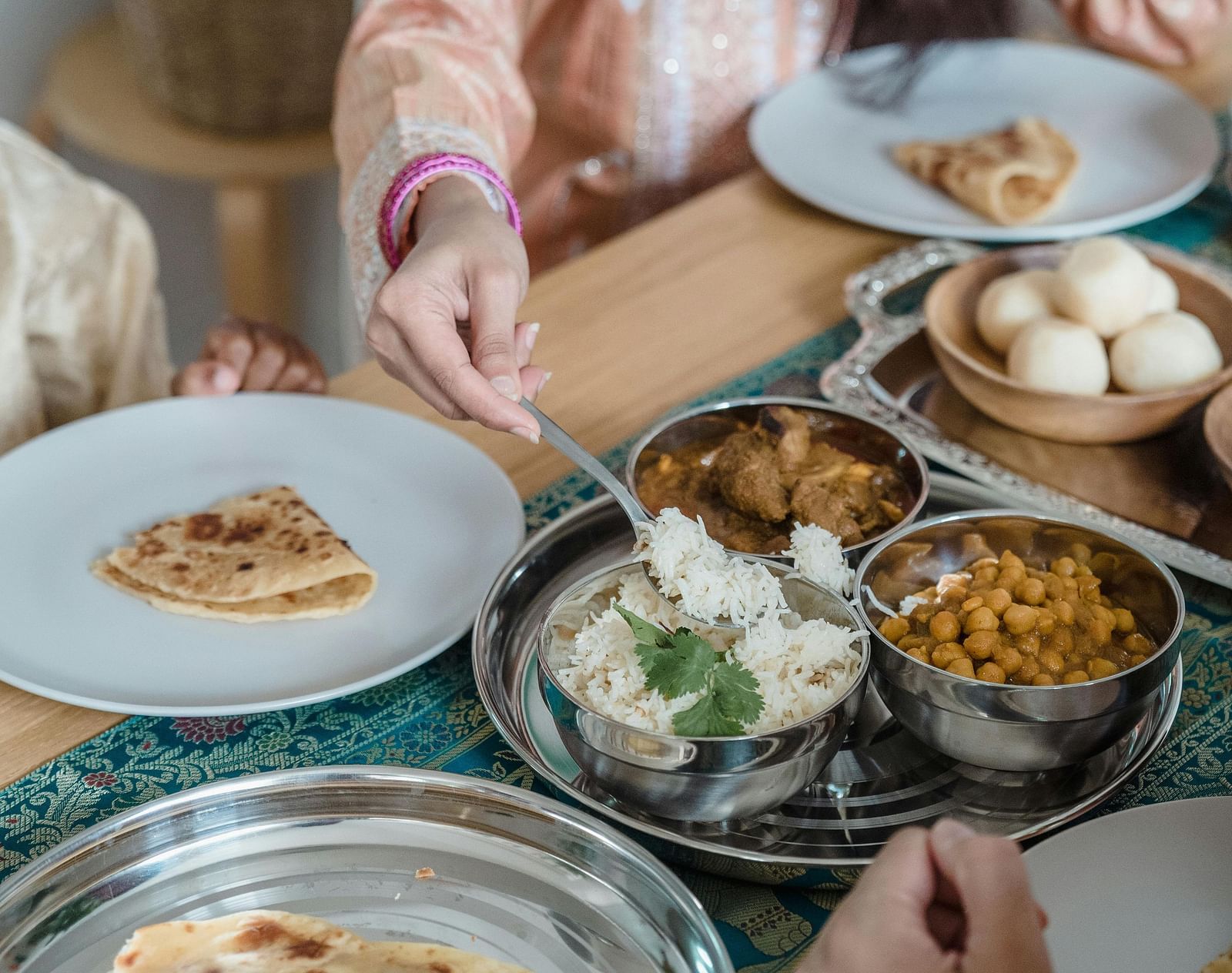 People sharing a meal with various dishes on a table, including flatbread and small bowls of food.