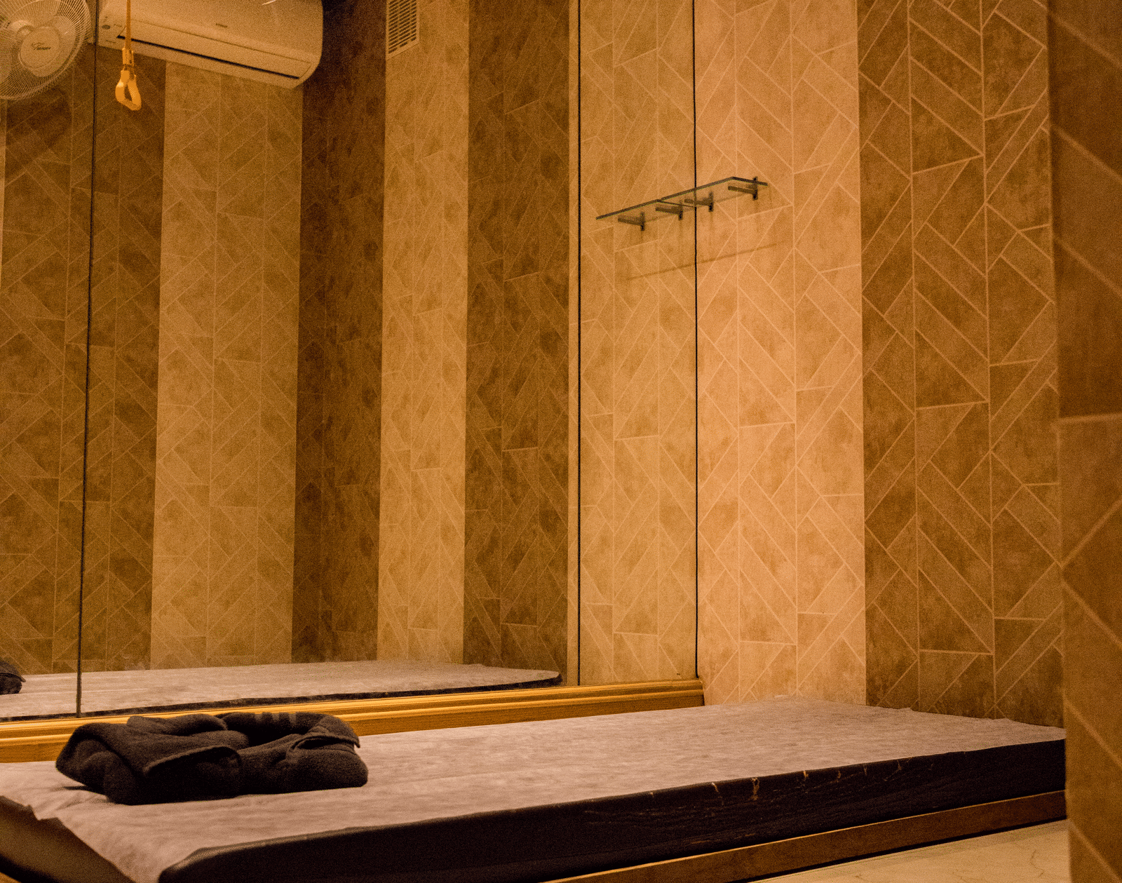 A mattress kept on the floor of a dimly lit room with a wall attached with full length mirror at Benzz Park, Vellore.