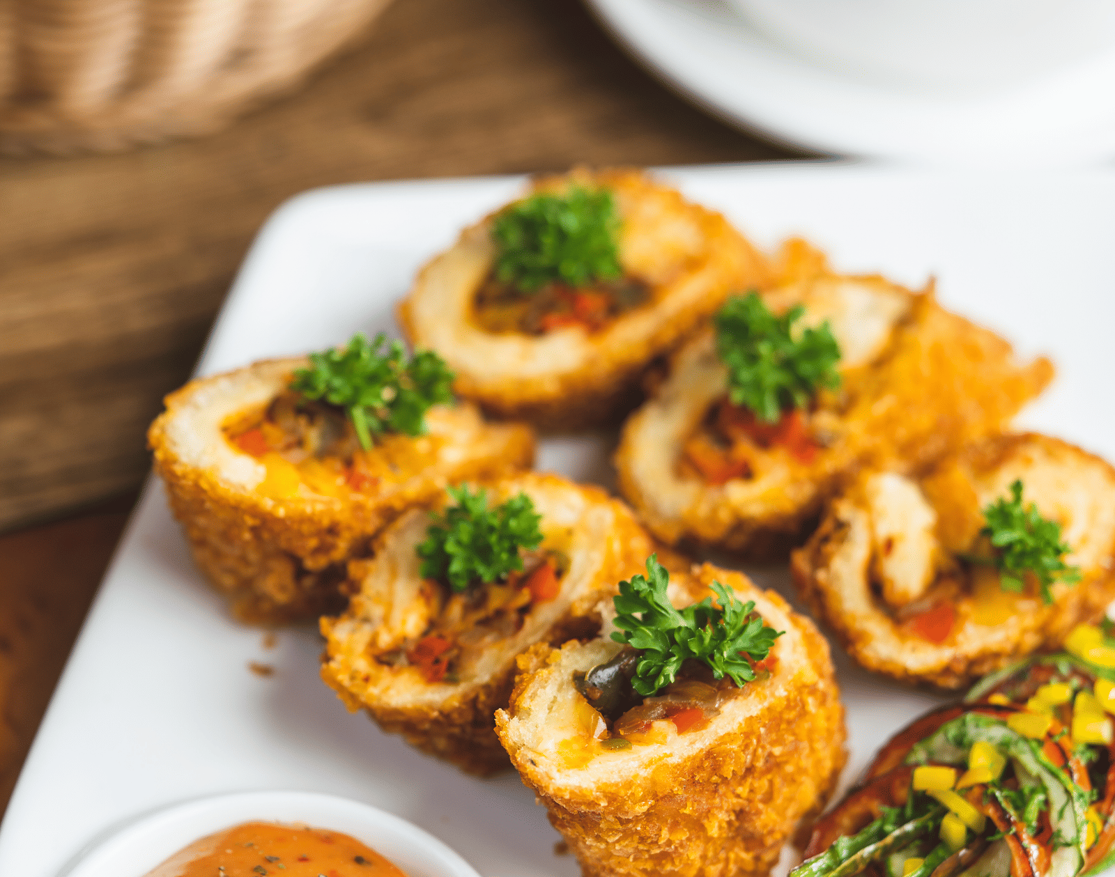 Close-up of an appetiser dish—fried rolls or snacks—served with a tangy dipping sauce on a white platter at Hotel Hukam's Lalit Mahal.