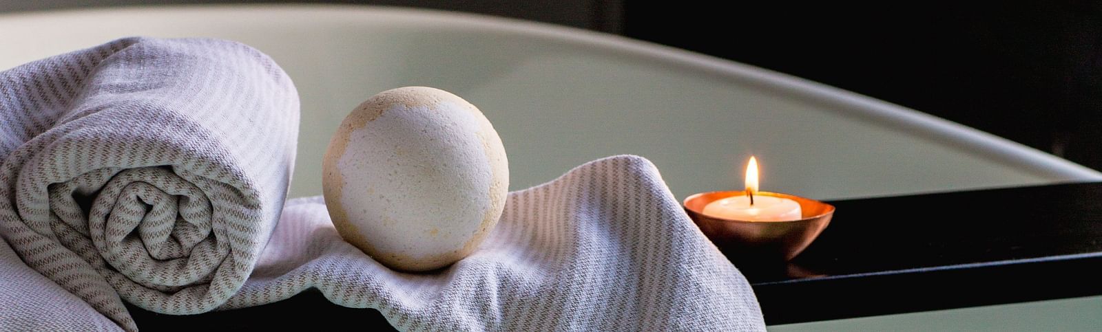 A tub filled with water along with towels and a candle