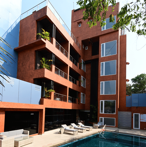 The outdoor swimming pool area with lounging chairs placed besides it at Golden Tulip Vagator, Goa