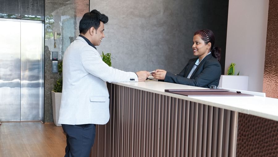 Guest interacting with a receptionist at the counter, handing over a card at TGI Livancia Hillside, JC Nagar, Mysore