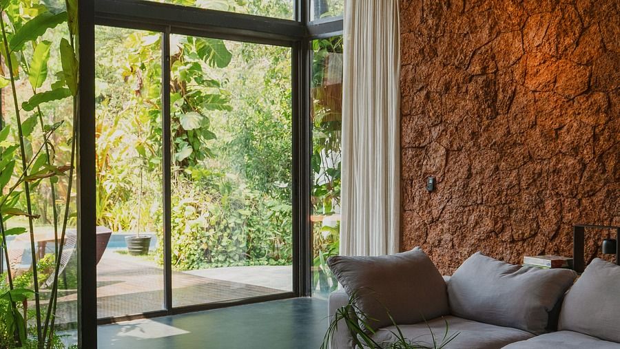 A modern villa with a glass wall overlooking a swimming pool.