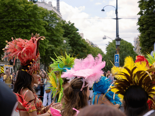 A crowd of people wearing costumes walking down the street under a bright sky