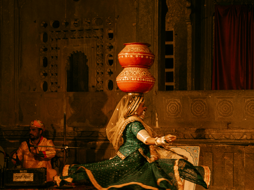 A female Rajasthani folk dancer with a couple of earthen pots on her head on the stage