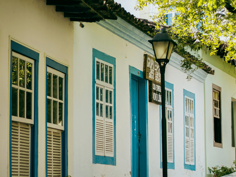 A street view of a colonial-style building with white walls, blue trim, and windows, next to a streetlamp.