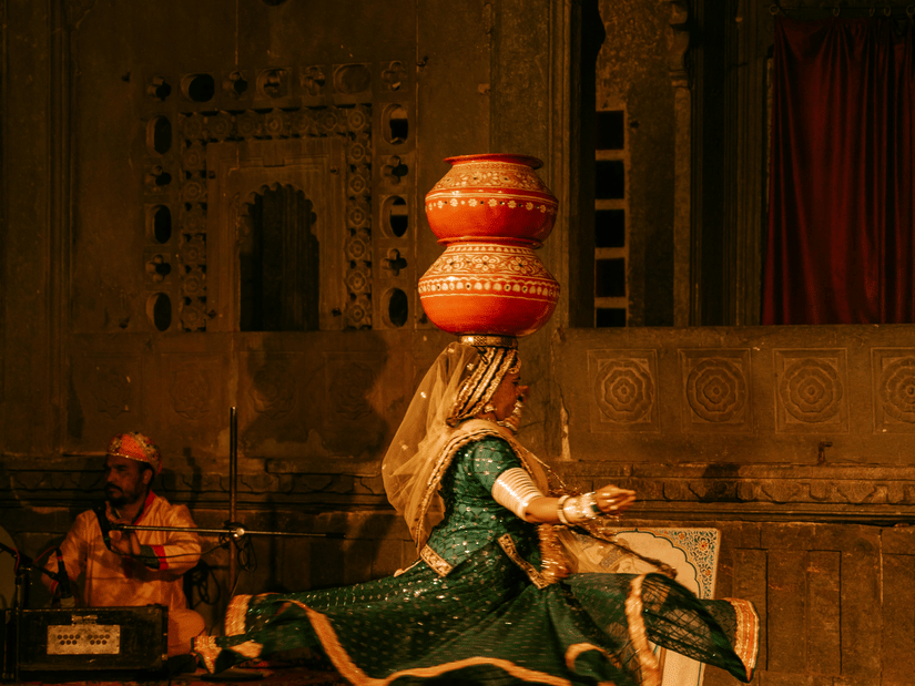 A female Rajasthani folk dancer with a couple of earthen pots on her head on the stage
