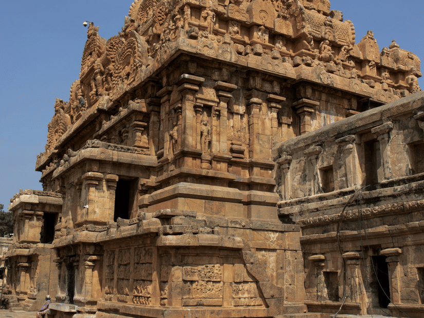 Brihadeeswara Temple under a blue sky featuring intricate carvings on a sunny day
