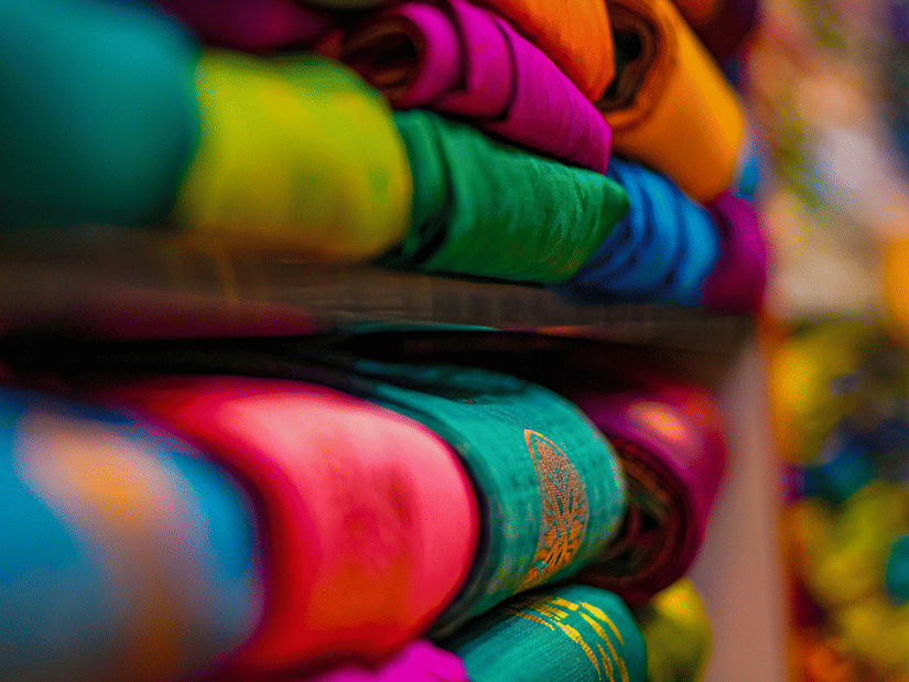 Stacks of brightly coloured handwoven cotton sarees displayed on shelves
