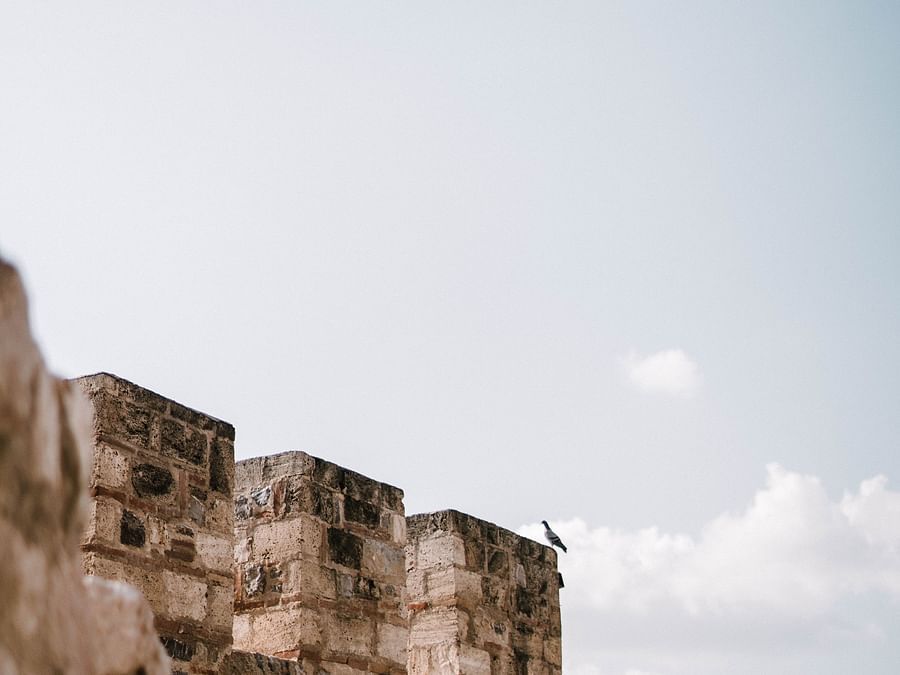 A view from afar of the top of a fort with blue sky in the background.