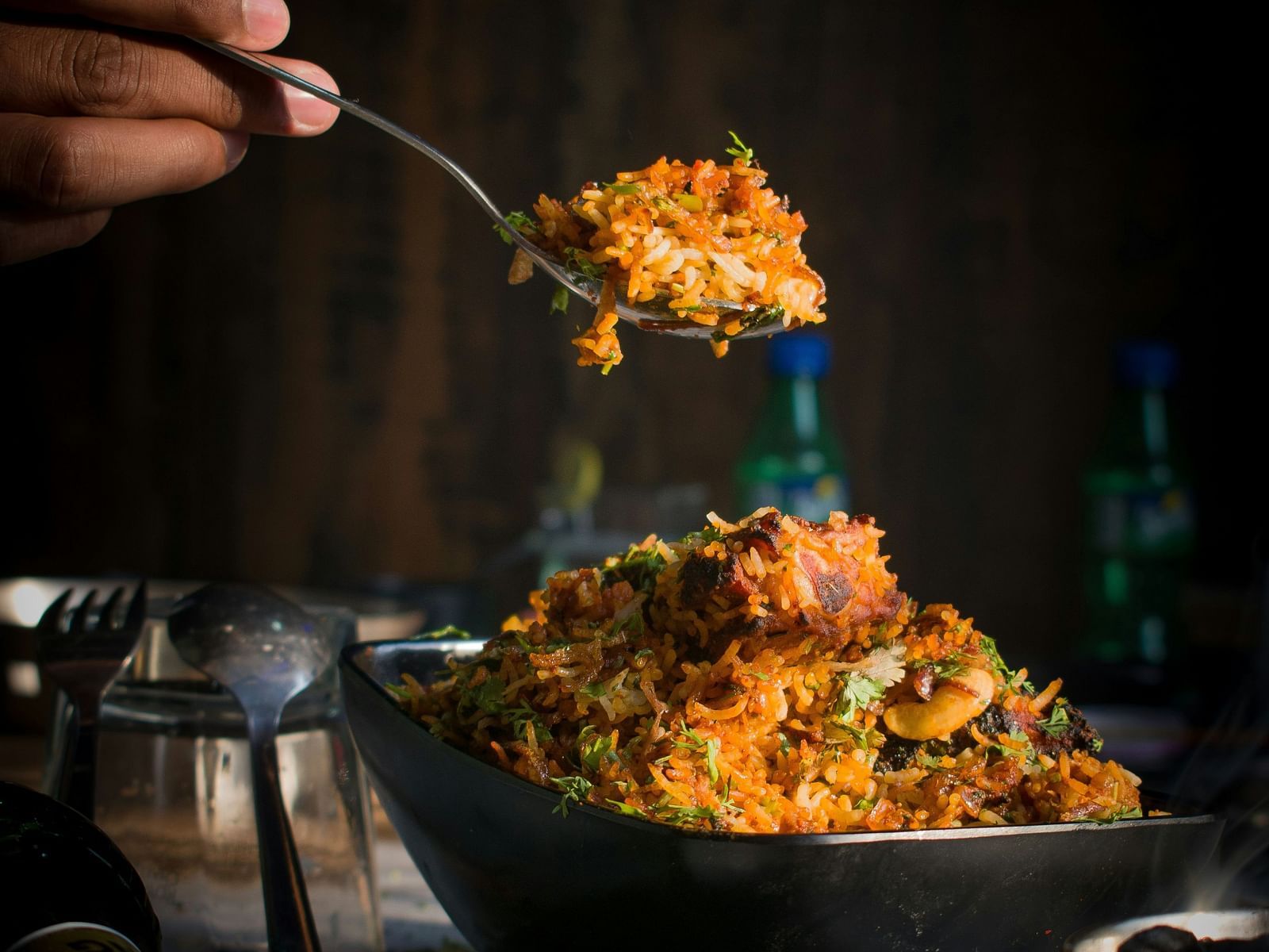 A close up of a person taking a spoonful of a biryani from the bowl below.