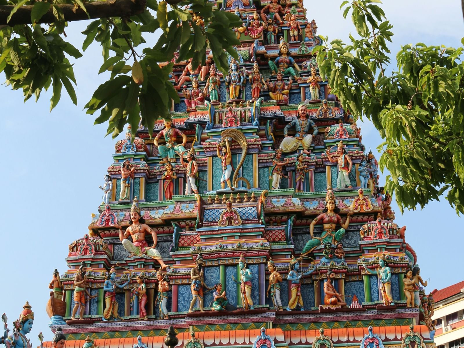 Golden temple tower, ornate design, foliage nearby.
