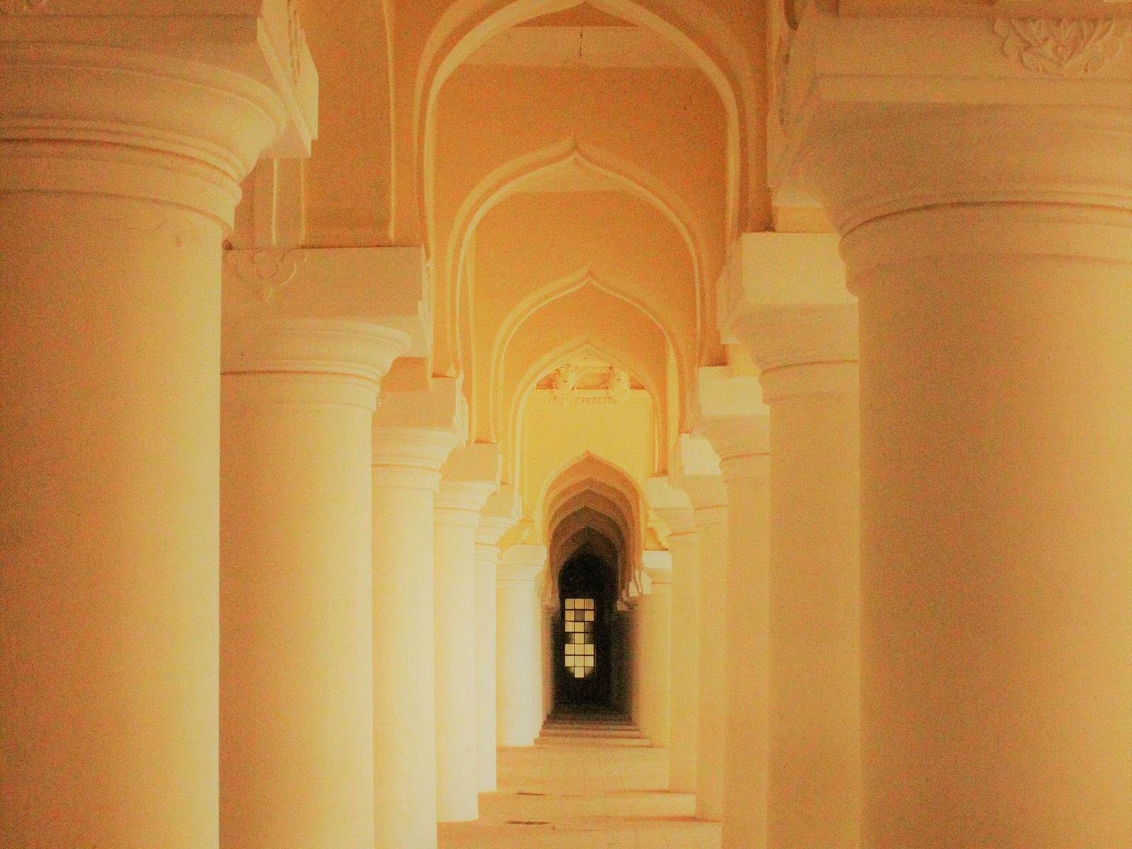 Illuminated archway inside Thirumalai Nayakkar Mahal captured in the evening.