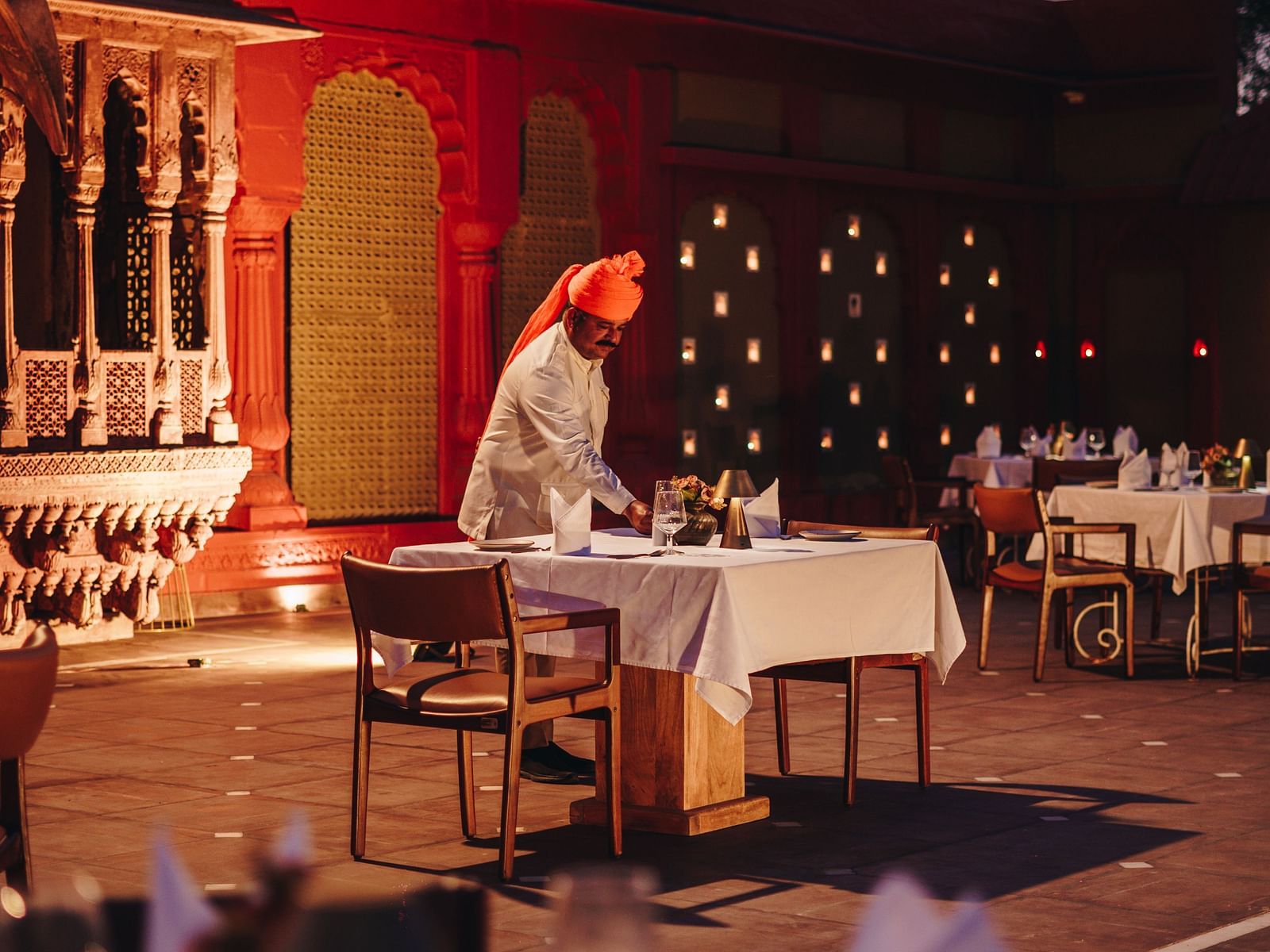 An outdoor dining setup with a traditionally dressed server at Surpura Bagh.