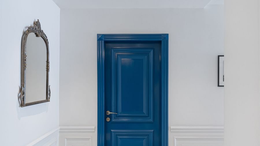  A corridor with a wall-mounted frame on one side leads to a door | Hotel Ganga Maiya