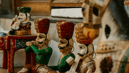 Wooden dolls of musicians and a horse on display with a mirror behind them