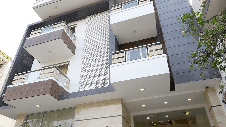 A multi-story building featuring exterior panels, with projecting balconies and a prominent glass facade at the entrance - Asian Suites Cyber Park, Gurgaon.