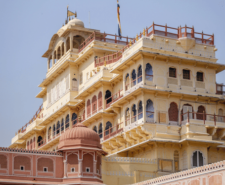 The city palace facade with pink sandstone exterior, rows of windows and balconies, and decorative architectural detailing.