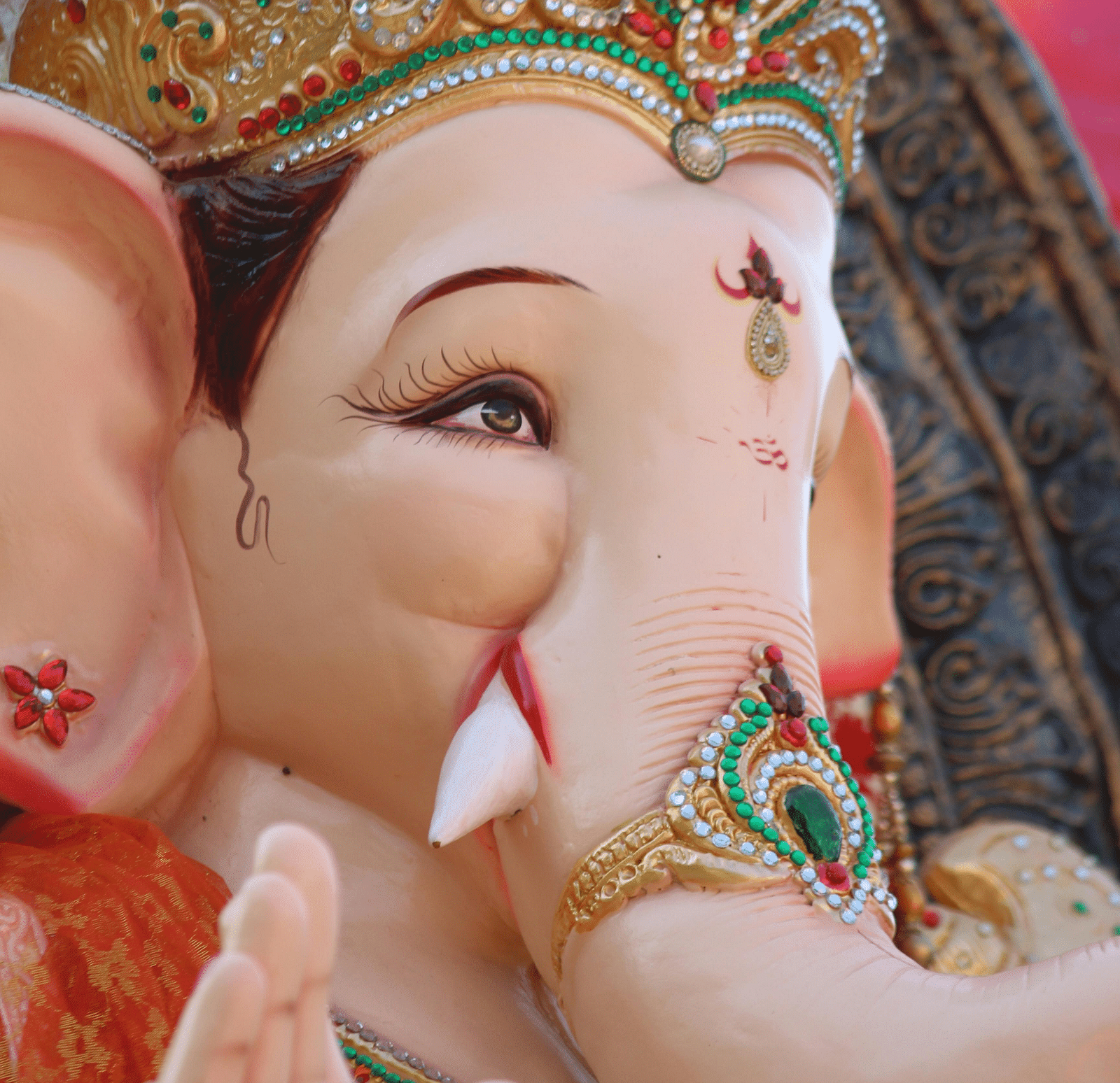 A close-up photograph shows a statue of the Hindu god Ganesha adorned with a decorative crown.