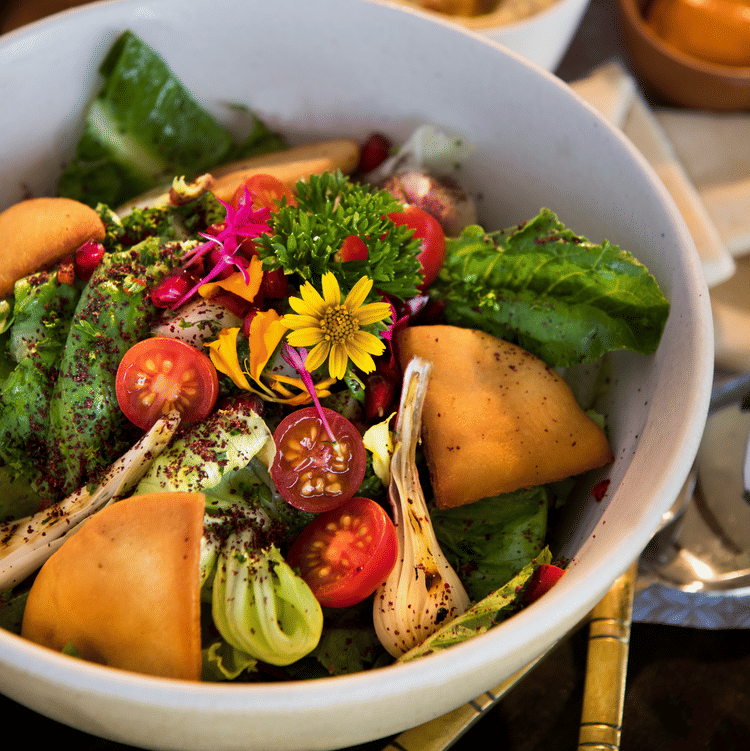 Colourful garden salad with lettuce, cherry tomatoes, cucumber, edible flowers & toasted bread—freshly served at Aramness.
