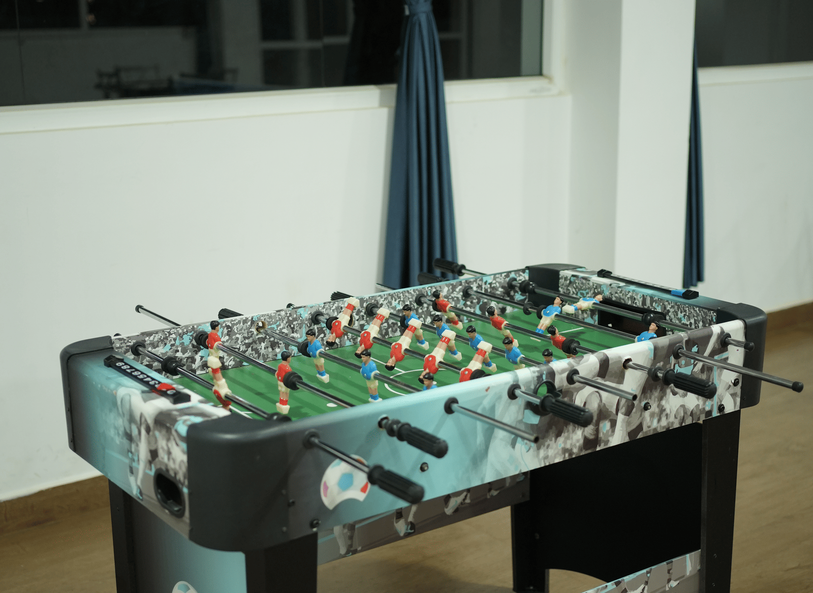 A close-up of a table football (foosball) game in a dimly lit, indoor games room at Coorg Orange Blossom Resort and Spa.