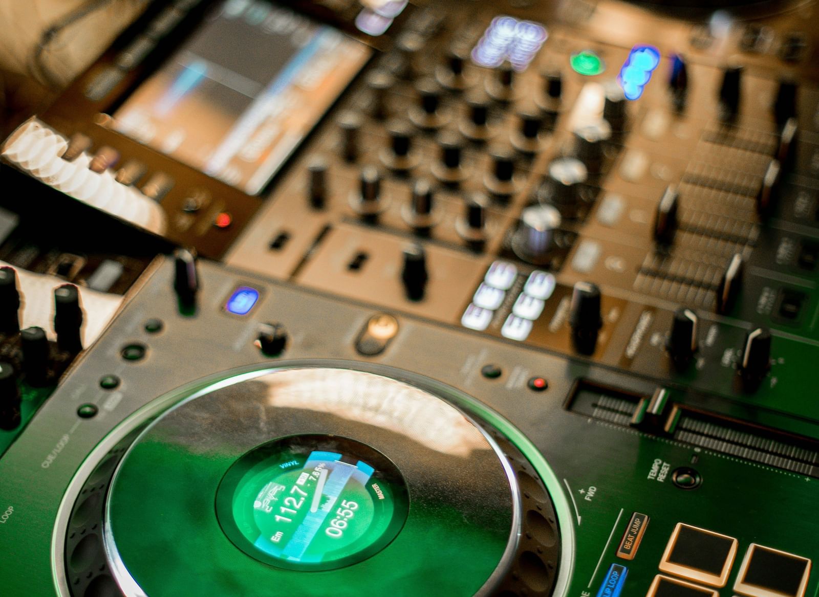 A close-up view of a DJ mixing console at Imperial Grande, showing various knobs, buttons, and a glowing green light.