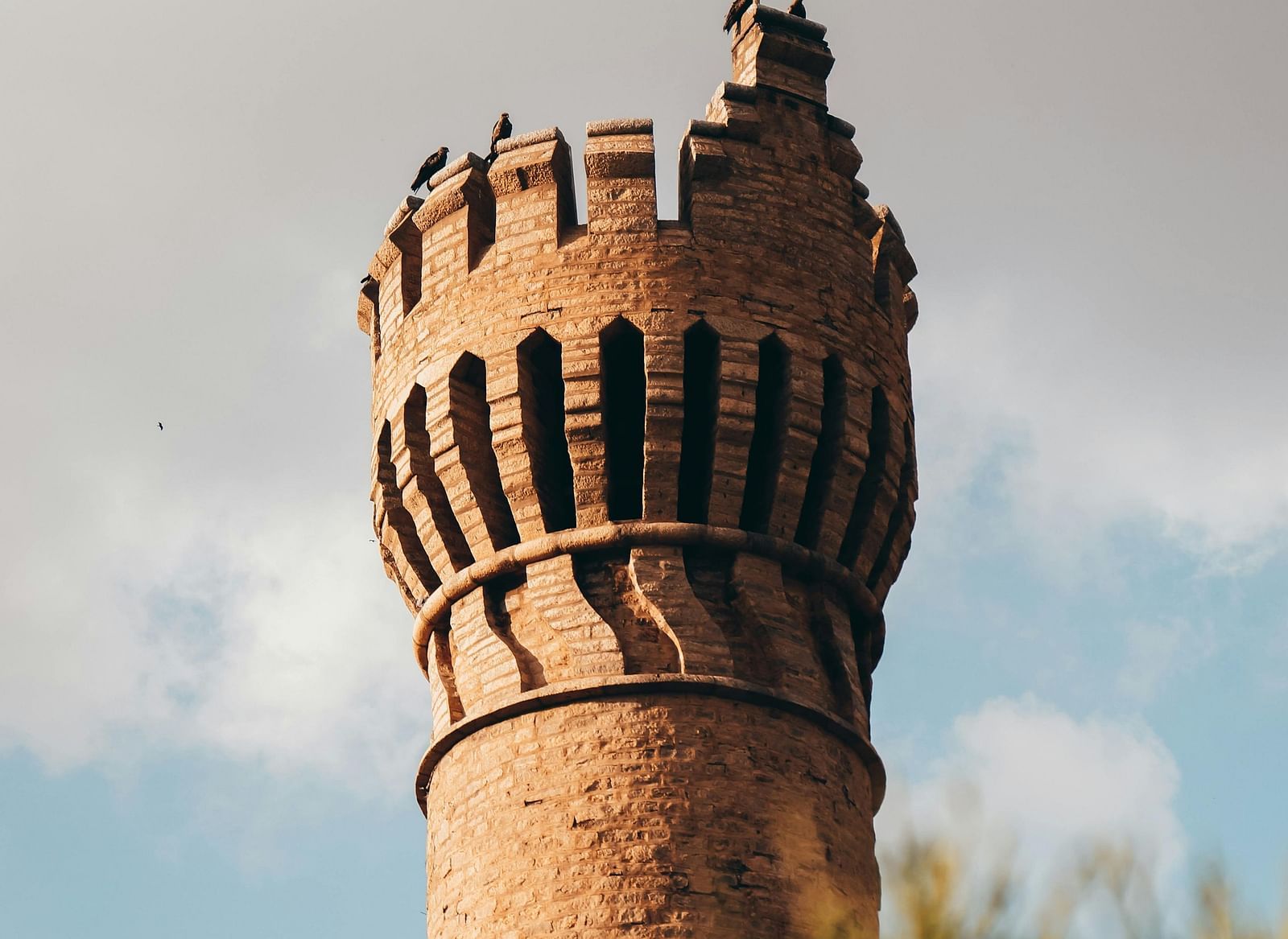 A stone tower of Bangalore fort with clouds in the background.