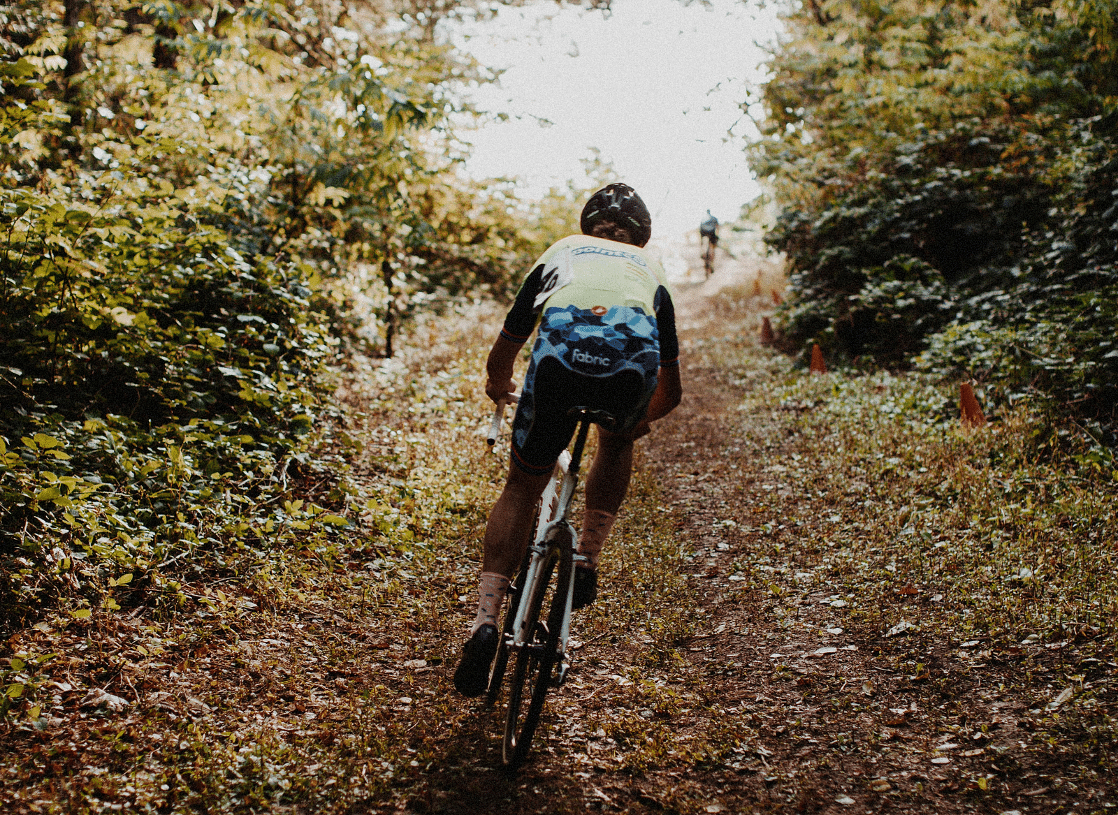 A person cycling along a trail surrounded by trees.