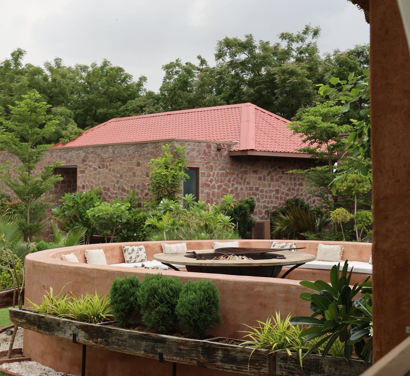 An indoor-outdoor restaurant at Surpura Bagh with wicker lamps, sheer white curtains, and a view of the resort's lush grounds.
