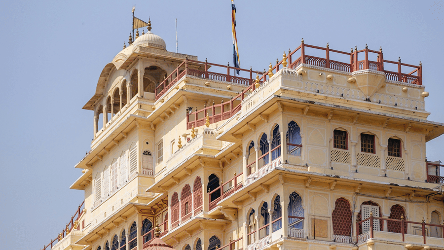 Low-angle view of a multi-tiered cream-coloured palace with intricate windows under a blue sky